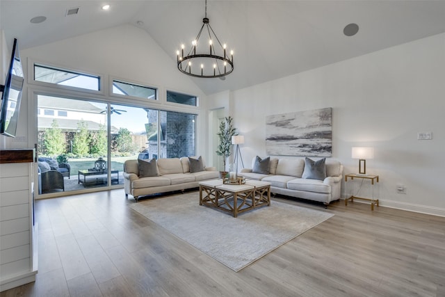 living room featuring light hardwood / wood-style floors, high vaulted ceiling, and a chandelier