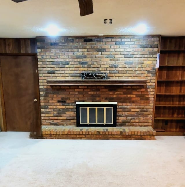 unfurnished living room with wood walls, carpet floors, and a brick fireplace