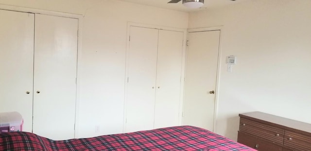 unfurnished bedroom with ceiling fan and two closets