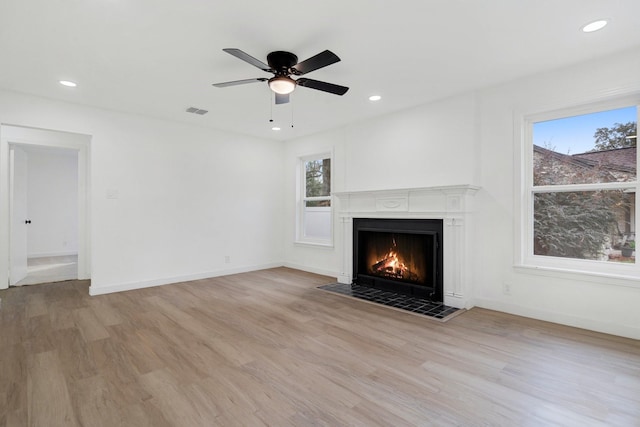 unfurnished living room featuring light hardwood / wood-style flooring, ceiling fan, and a tiled fireplace