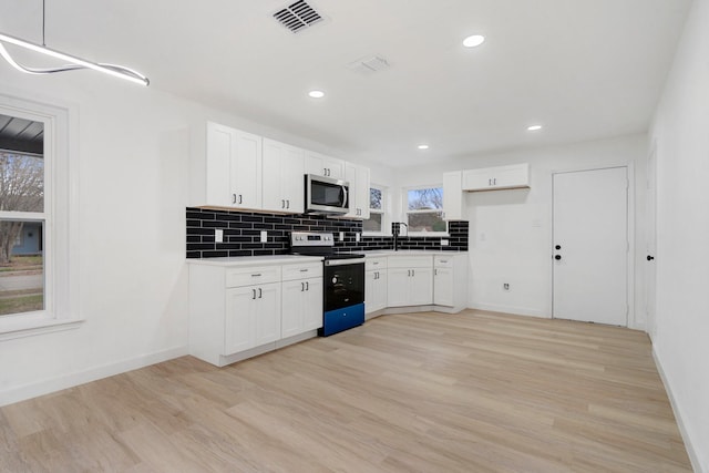 kitchen with electric range oven, white cabinetry, hanging light fixtures, and light hardwood / wood-style flooring