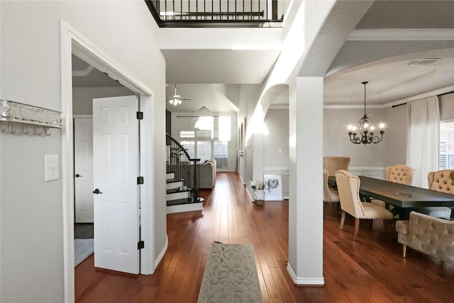 foyer featuring dark hardwood / wood-style flooring, crown molding, plenty of natural light, and ceiling fan with notable chandelier