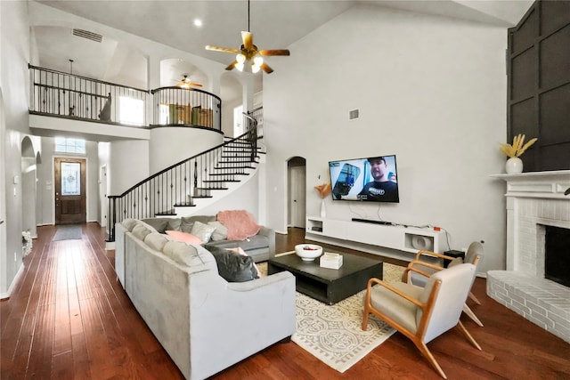 living room featuring a high ceiling, ceiling fan, dark hardwood / wood-style floors, and a fireplace