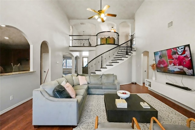 living room with ceiling fan, a towering ceiling, and dark hardwood / wood-style flooring