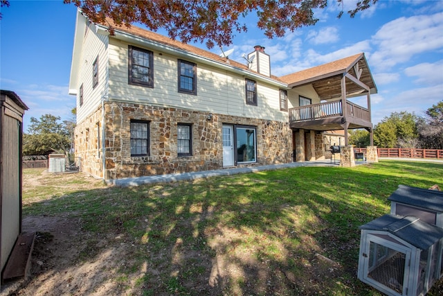 rear view of property with a balcony and a lawn