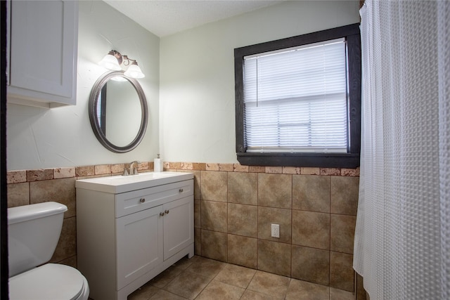 bathroom with tile patterned flooring, vanity, tile walls, and toilet