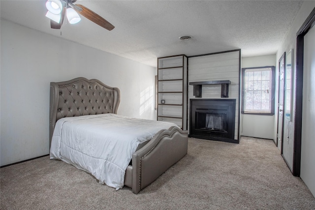 carpeted bedroom with ceiling fan and a textured ceiling