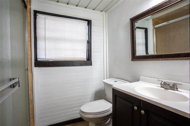 bathroom with a shower with door, vanity, and toilet