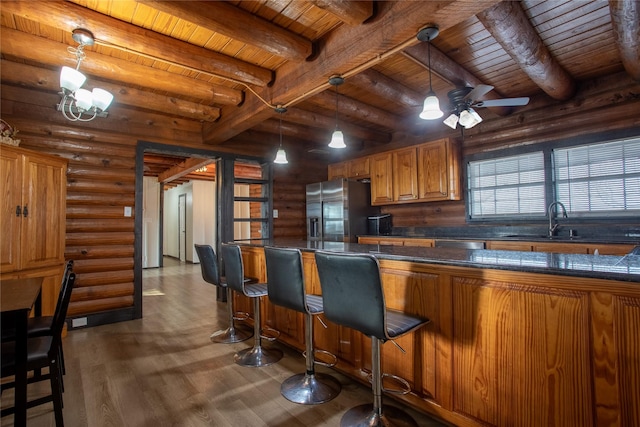 kitchen with a kitchen bar, sink, decorative light fixtures, wooden ceiling, and stainless steel appliances