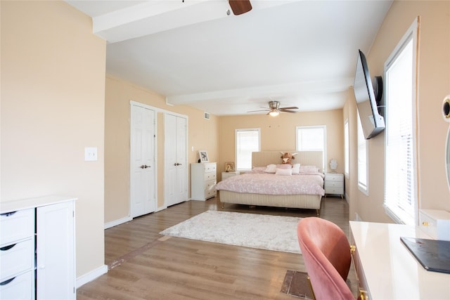 bedroom featuring two closets, light hardwood / wood-style flooring, and ceiling fan