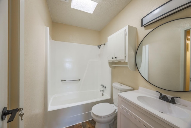 full bathroom featuring a skylight, bathtub / shower combination, vanity, toilet, and a textured ceiling