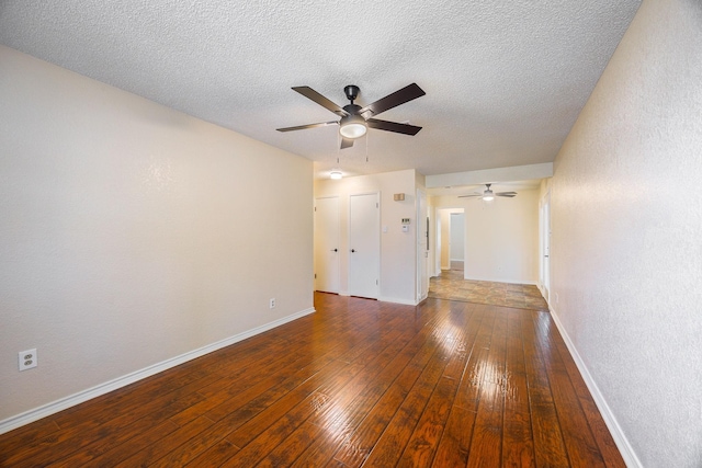 unfurnished room featuring ceiling fan, dark wood-type flooring, and a textured ceiling