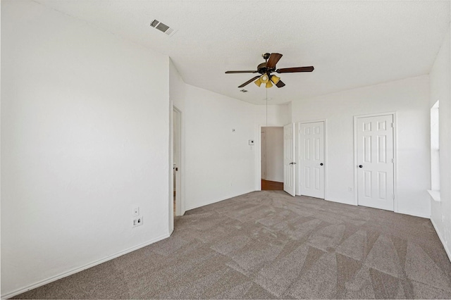 unfurnished bedroom with multiple closets, light colored carpet, and ceiling fan