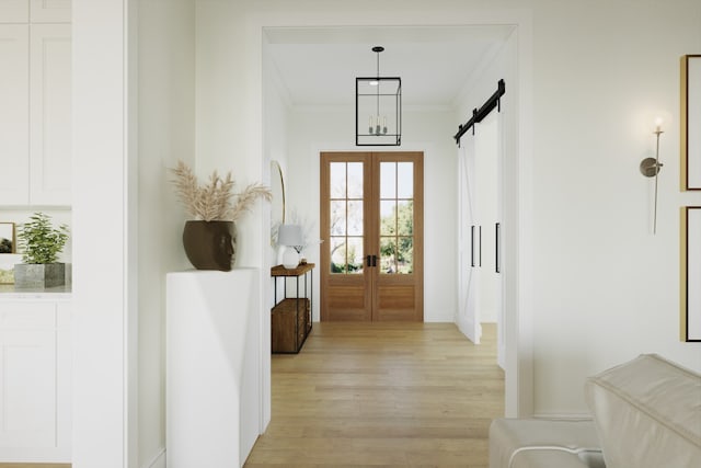 hallway with a barn door, light wood-style floors, french doors, and ornamental molding