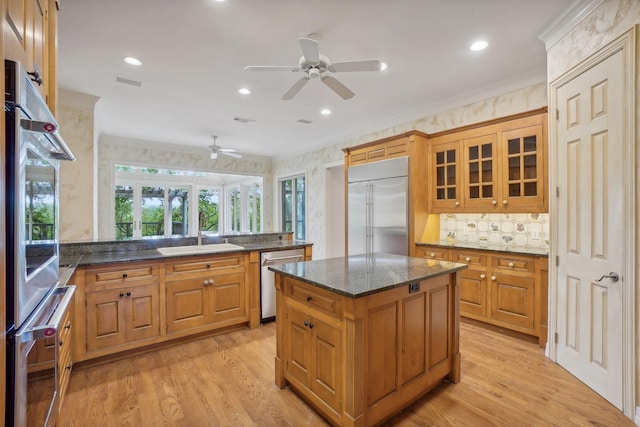 kitchen featuring kitchen peninsula, dark stone countertops, appliances with stainless steel finishes, a kitchen island, and light wood-type flooring