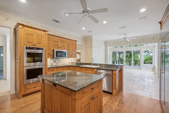 kitchen featuring kitchen peninsula, appliances with stainless steel finishes, ceiling fan, sink, and dark stone countertops