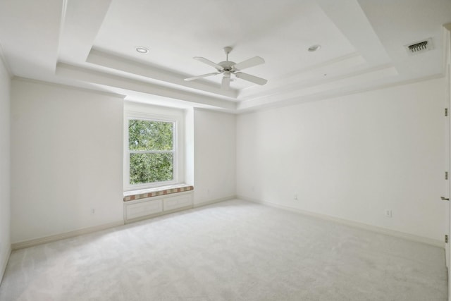 carpeted empty room featuring a raised ceiling and ceiling fan