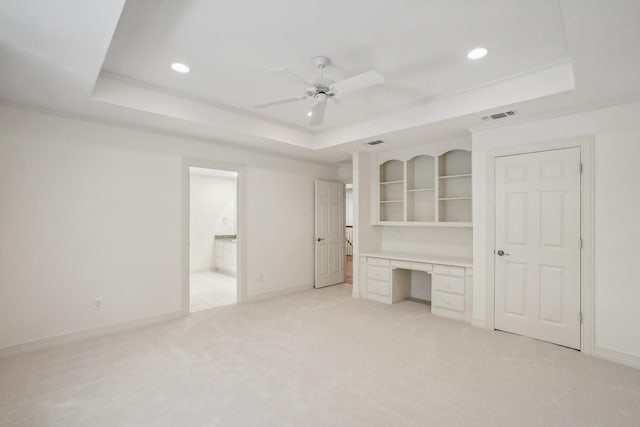 unfurnished bedroom with a tray ceiling, ceiling fan, and light colored carpet