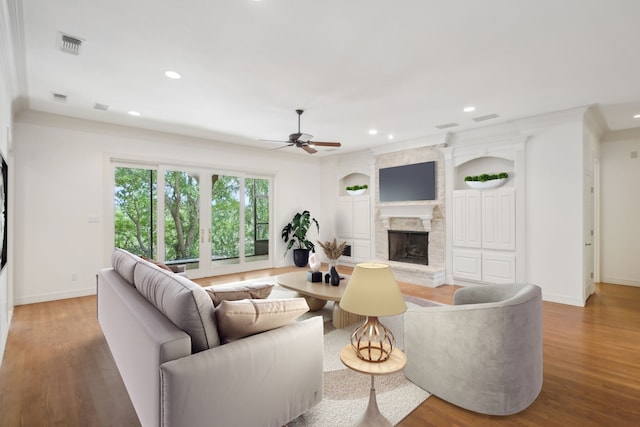 living room featuring a fireplace, hardwood / wood-style floors, ceiling fan, and ornamental molding