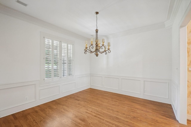 empty room featuring crown molding, hardwood / wood-style floors, and a notable chandelier