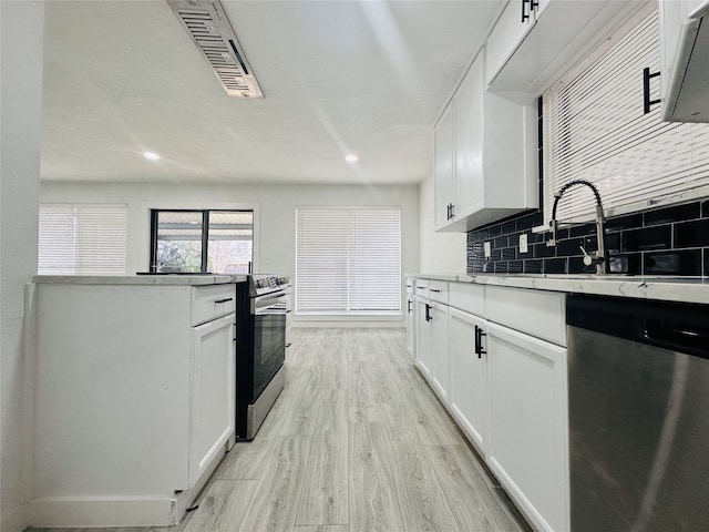 kitchen with sink, light hardwood / wood-style flooring, tasteful backsplash, white cabinetry, and stainless steel appliances