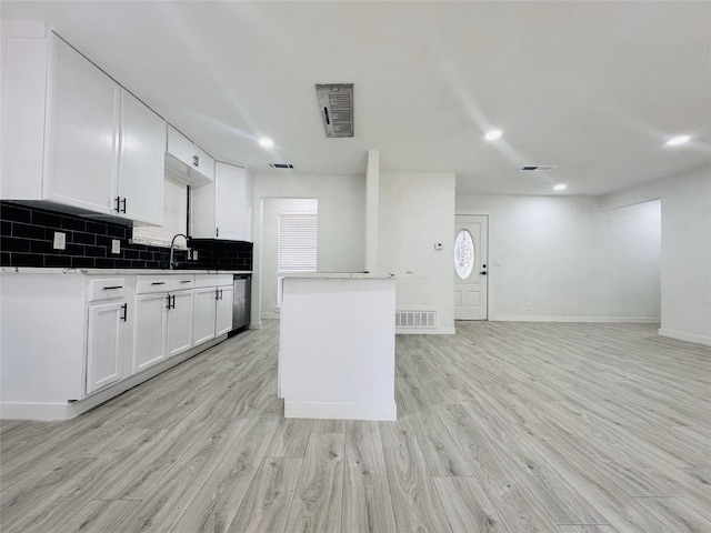 kitchen with decorative backsplash, light wood-type flooring, stainless steel dishwasher, sink, and white cabinets