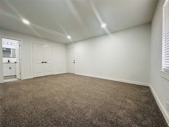 unfurnished bedroom featuring ensuite bath, a closet, carpet floors, and sink