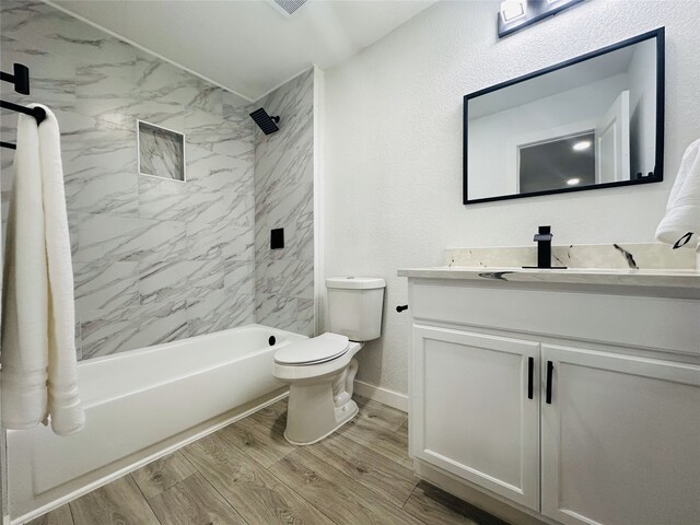 full bathroom featuring hardwood / wood-style flooring, tiled shower / bath combo, toilet, and vanity