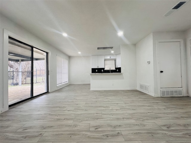 unfurnished living room featuring light wood-type flooring and sink