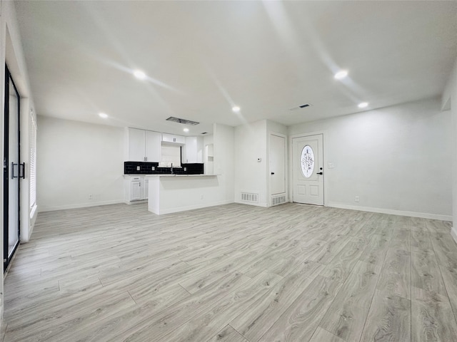 unfurnished living room featuring sink and light hardwood / wood-style floors