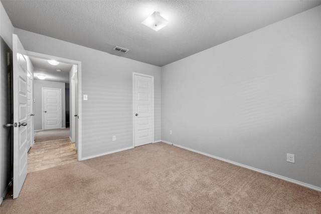 unfurnished bedroom featuring a textured ceiling and light carpet