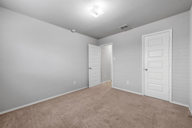 unfurnished bedroom with a closet, a textured ceiling, and light colored carpet