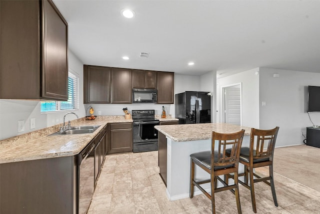 kitchen with sink, a kitchen bar, dark brown cabinetry, a kitchen island, and black appliances