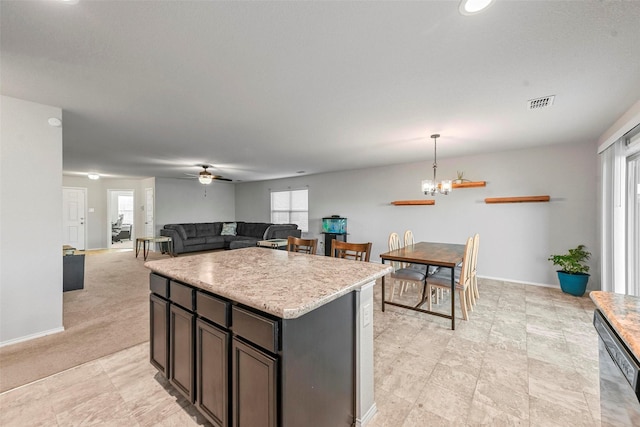 kitchen with light carpet, stainless steel dishwasher, hanging light fixtures, dark brown cabinetry, and plenty of natural light