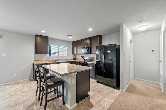 kitchen featuring a center island, black appliances, a breakfast bar area, dark brown cabinets, and sink