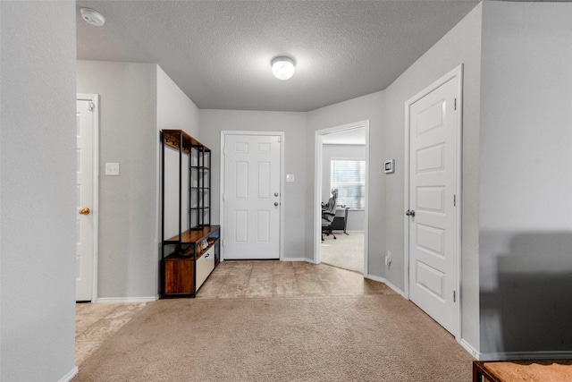 entrance foyer with a textured ceiling and light carpet