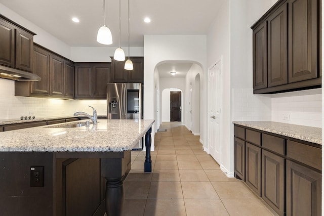 kitchen featuring sink, a breakfast bar area, a center island with sink, light tile patterned flooring, and stainless steel fridge with ice dispenser