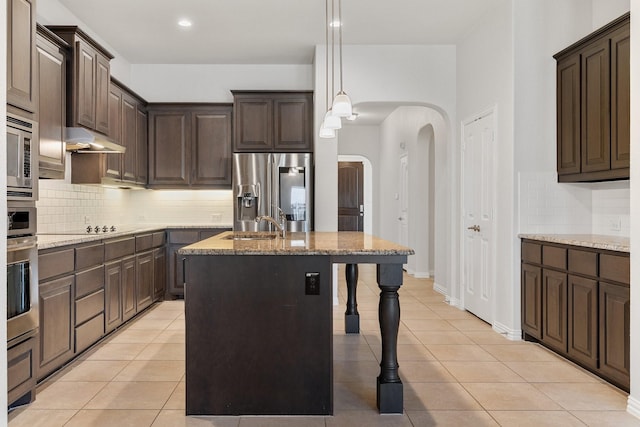 kitchen featuring pendant lighting, light tile patterned floors, a breakfast bar, a kitchen island with sink, and stainless steel appliances