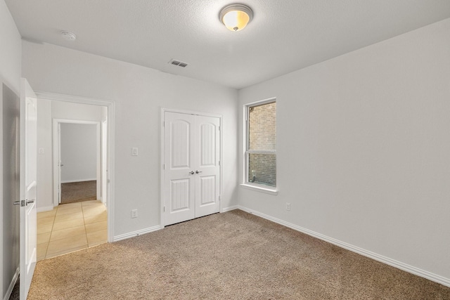 unfurnished bedroom featuring carpet floors, a closet, and a textured ceiling