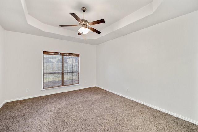 carpeted spare room featuring a raised ceiling and ceiling fan