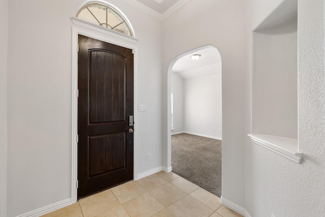 foyer entrance with ornamental molding and light tile patterned floors