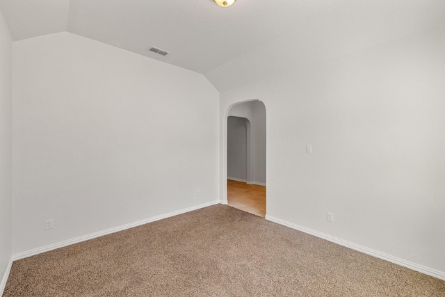 spare room with vaulted ceiling and light colored carpet