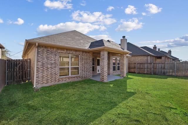 back of house with a yard and a patio