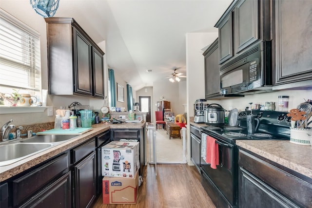 kitchen with plenty of natural light, lofted ceiling, black appliances, sink, and dark brown cabinets