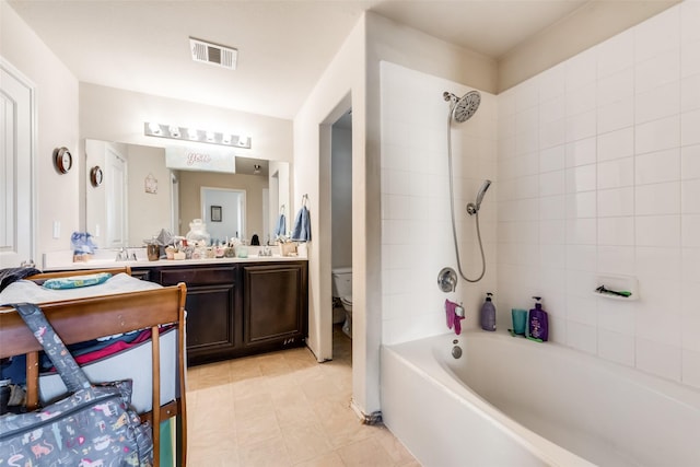 full bathroom with tile patterned floors, vanity, tiled shower / bath, and toilet