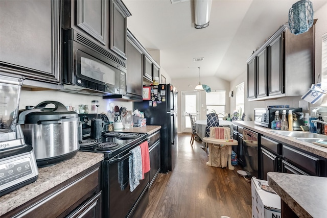 kitchen featuring dark hardwood / wood-style flooring, sink, black appliances, hanging light fixtures, and lofted ceiling