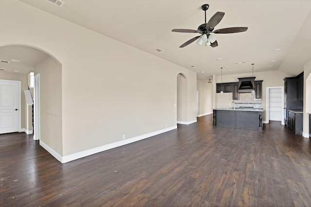 unfurnished living room featuring sink, dark wood-type flooring, ceiling fan, and vaulted ceiling