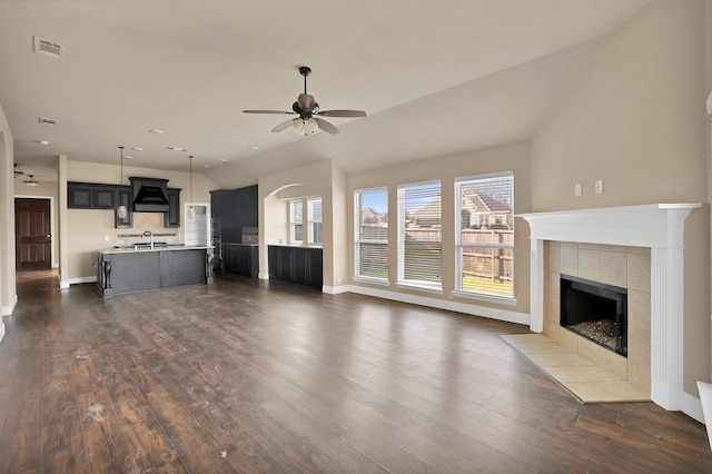 unfurnished living room featuring vaulted ceiling, dark wood-type flooring, ceiling fan, and a fireplace