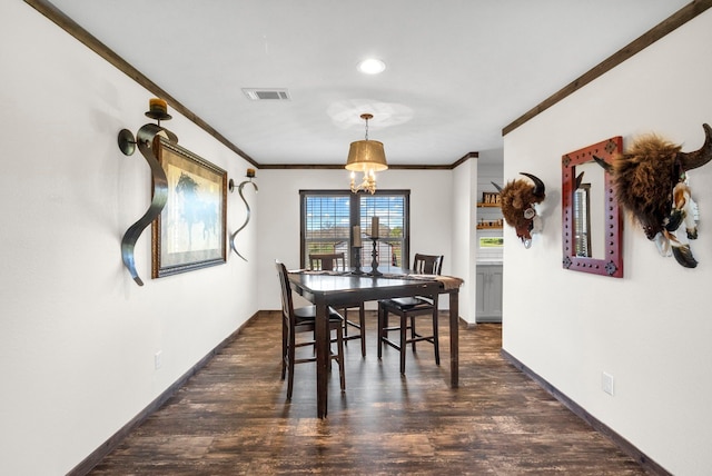 dining space featuring ornamental molding, a chandelier, visible vents, and dark wood-type flooring