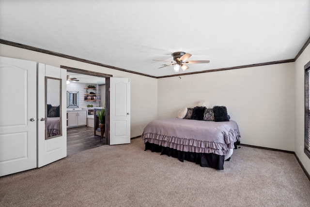 carpeted bedroom with a ceiling fan, ensuite bath, baseboards, and crown molding